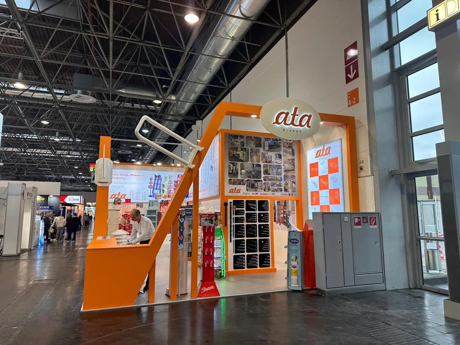 Ata Dizayn’ın EuroShop 2026’daki turuncu çerçeveli A58 standının fuar koridorundan görünümü